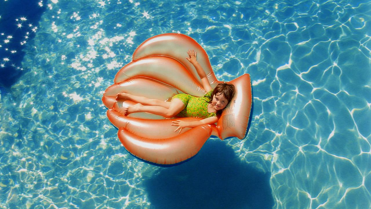 little girl on a pool toy in the water