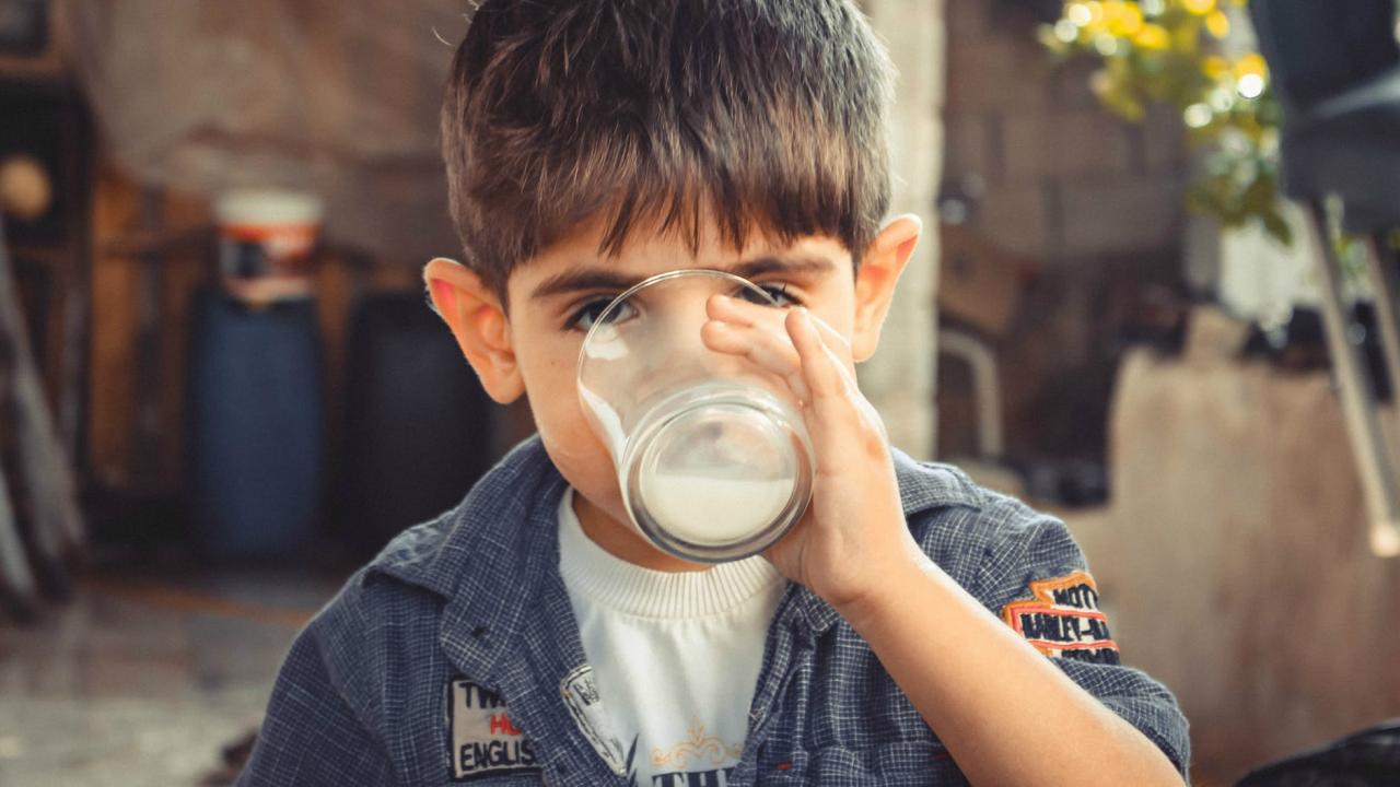 a boy drinking a glass of milk