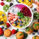 a smoothie bowl with fresh fruit, almonds, and muffins