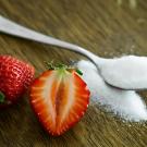 strawberry next to a tablespoon of sugar
