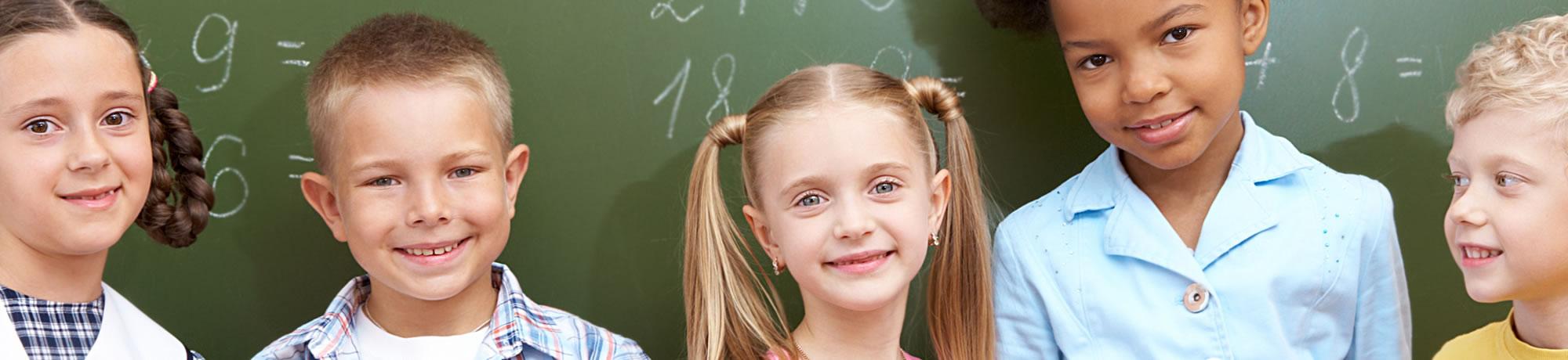 Kids smiling infront of a board.